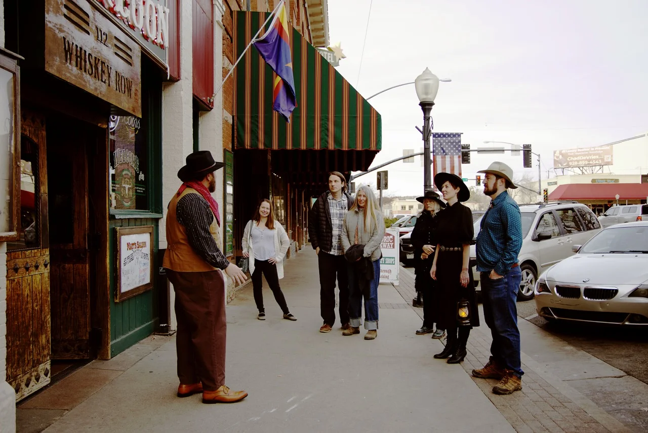 A costumed Freaky Foot Tours guide telling stories to a daytime walking group in historic downtown Prescott, Arizona
